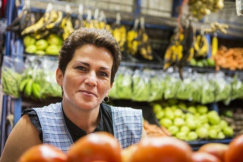 A person in a market aisle with various fruits and vegetables on display. 2