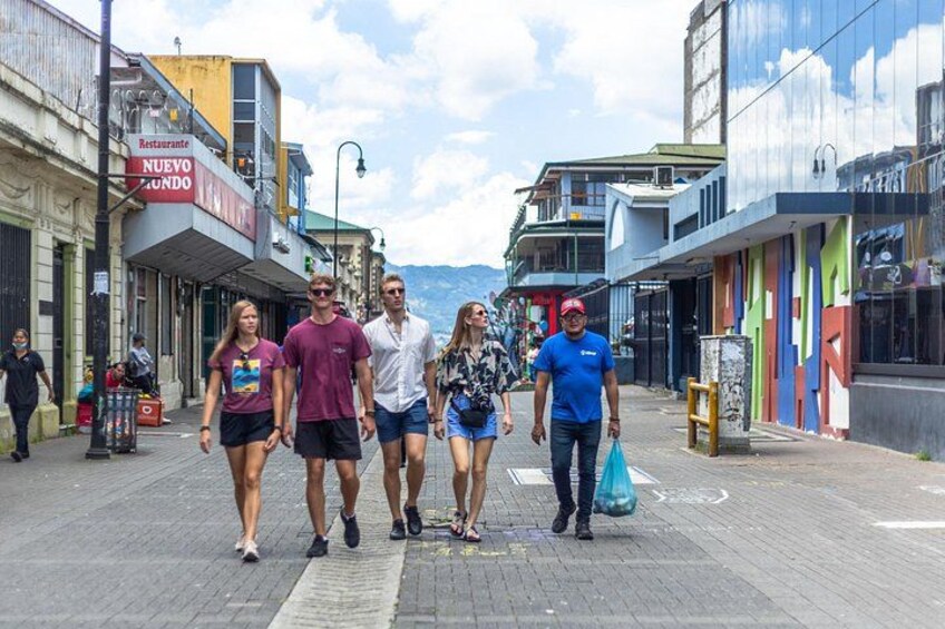 A group of people walking on a pedestrian street with shops and colorful buildings. 4