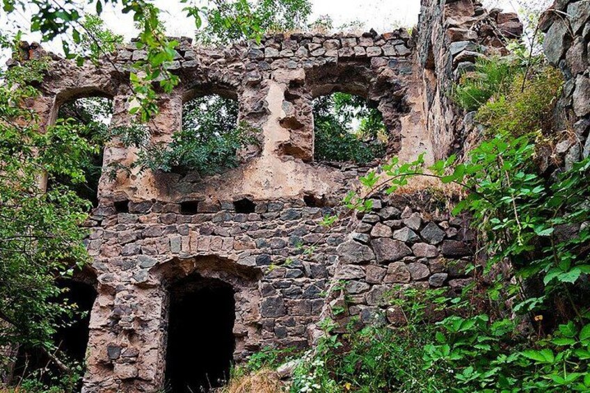 A stone ruin with arched openings and overgrown vegetation. 2