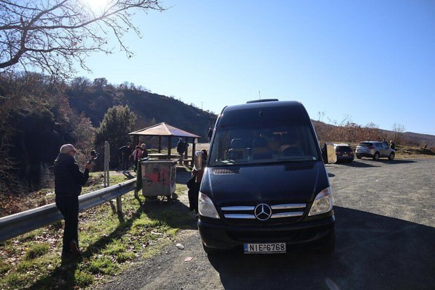 Un Mercedes-Benz negro estacionado en un camino de grava con una barandilla y una pequeña estructura al fondo. 3