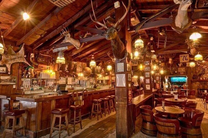 A rustic bar with wooden beams, antlers, and vintage decor. 4