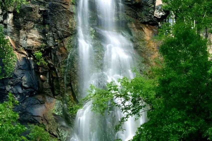 A waterfall cascading over rocky terrain surrounded by lush greenery. 5