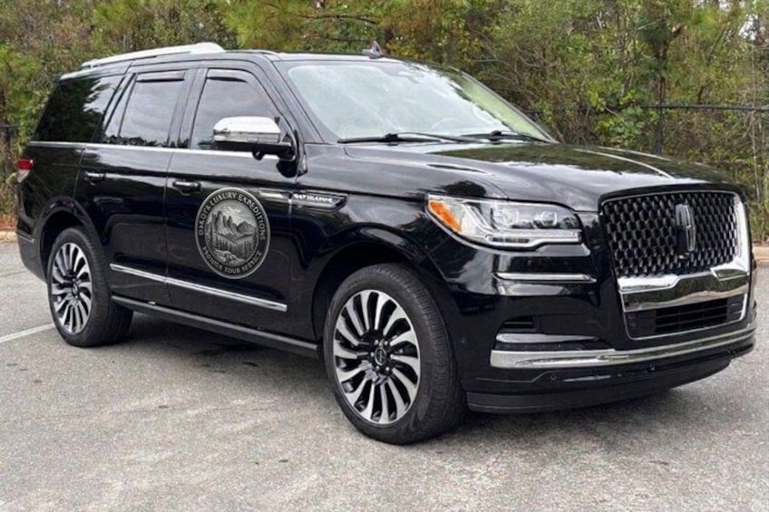 A black SUV parked on a paved surface with a logo on the side. 2