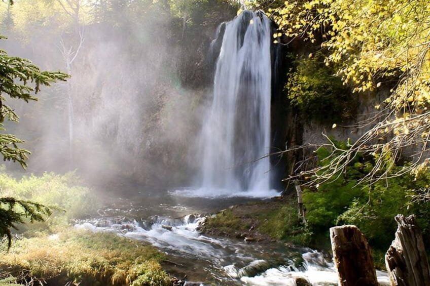 A waterfall in a forested area with mist rising from the water. 4