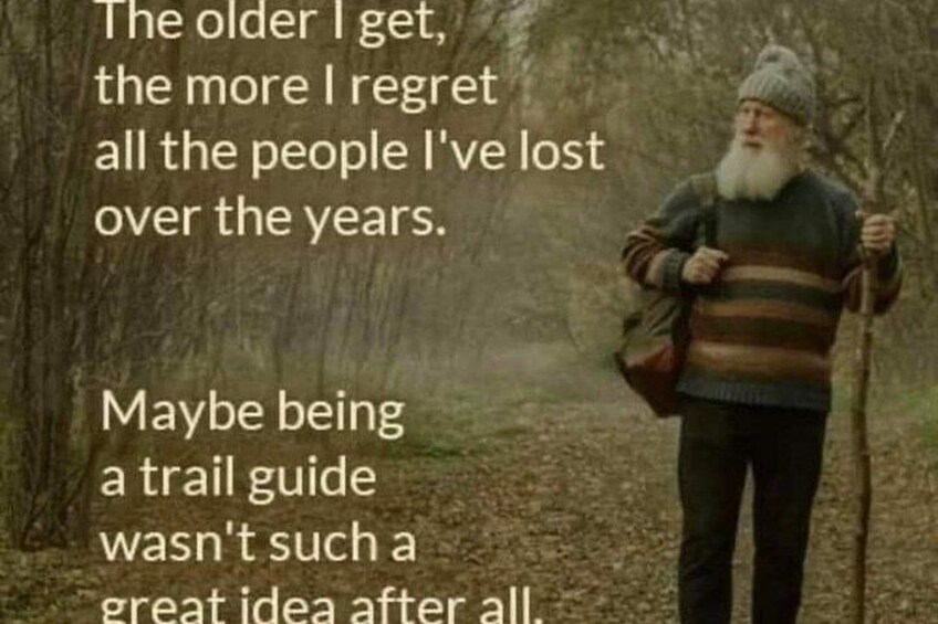 An elderly man walking in a forest with a backpack and a walking stick. 3