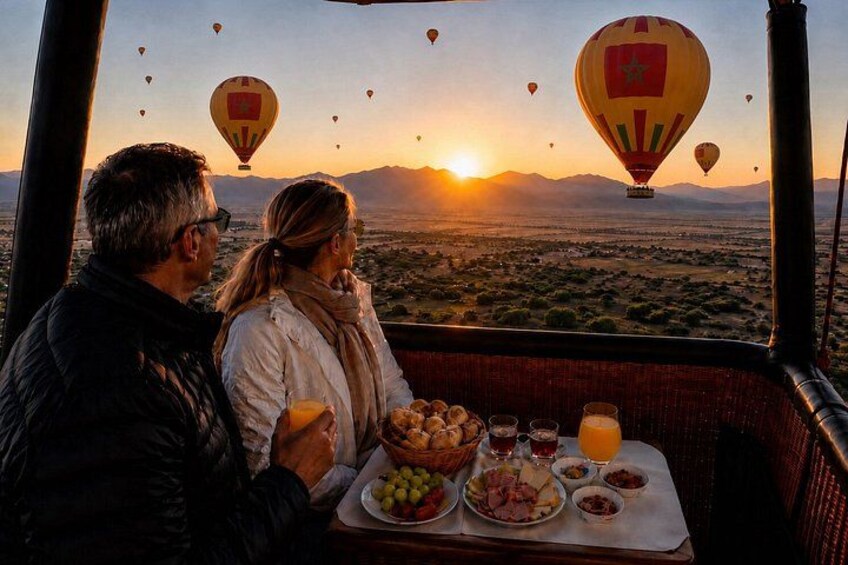 Un couple dînant à l’intérieur d’un véhicule, avec un paysage désertique et des montgolfières en arrière-plan. 1
