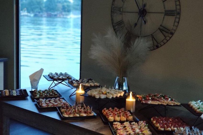 A buffet table with various food items, candles, and a clock on the wall. 5