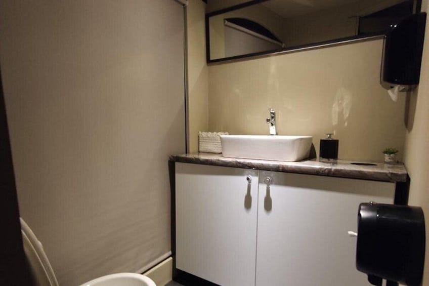 A bathroom with a white sink, a mirror, and a black hand dryer. 4