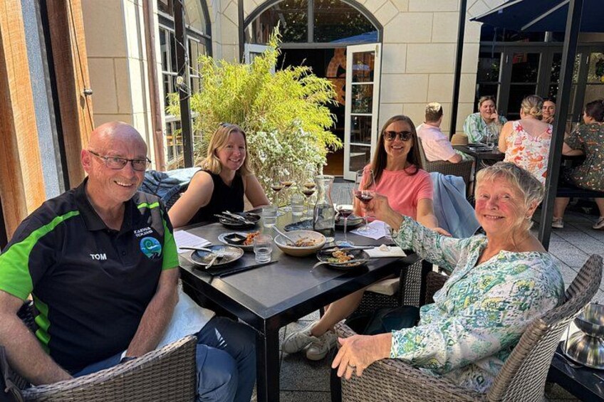 Un grupo de personas cenando al aire libre en una mesa con comida y bebidas. 3