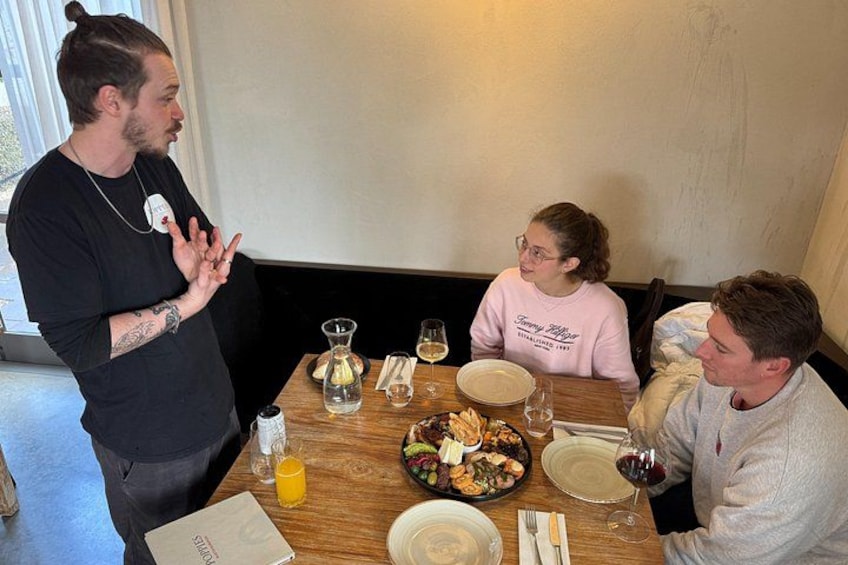 Una mesa de comedor con comida, bebidas y una persona de pie. 2