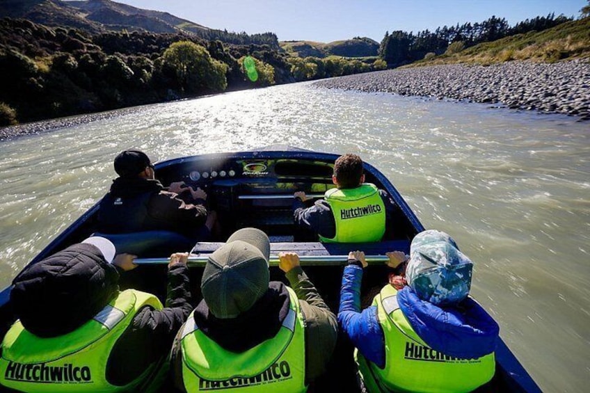 Eine Gruppe von Menschen in einem Boot auf einem Fluss, mit Rettungswesten mit dem 'Hutchwico'-Branding. 1
