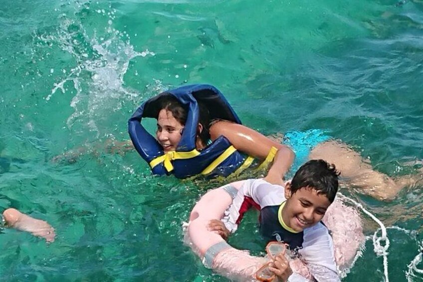 Zwei Personen treiben auf dem Wasser, eine trägt eine Schwimmweste, die andere hält ein Getränk. 5