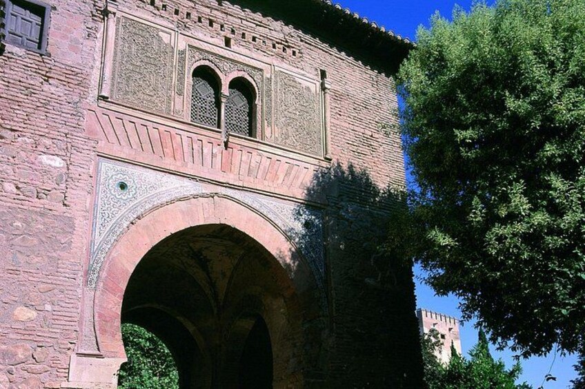 A historic stone building with an arched entrance and intricate tile work. 2