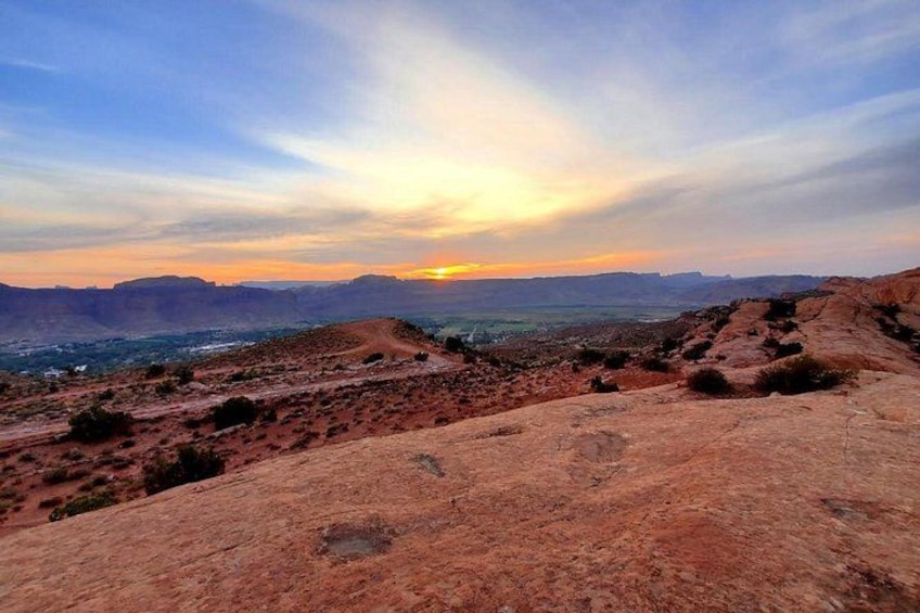 A desert landscape with a sunset, rocky terrain, and distant hills. 5