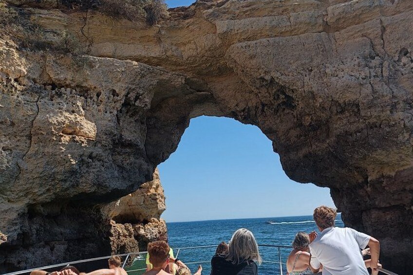 A rocky arch formation with people observing the ocean. 2