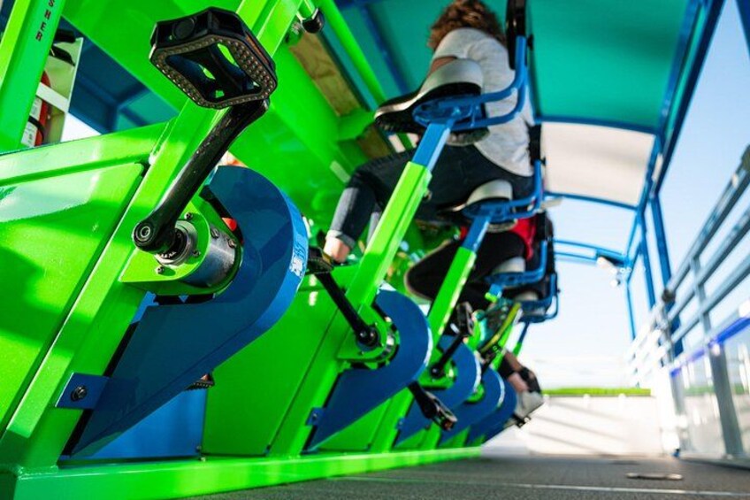 A green and blue amusement ride with passengers seated. 2
