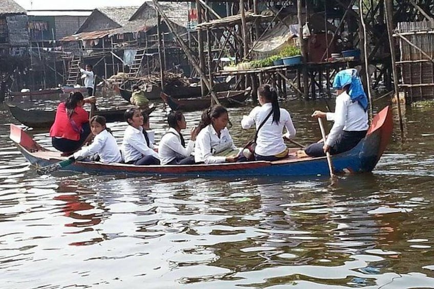A group of people in a boat on a river, surrounded by wooden structures. 1