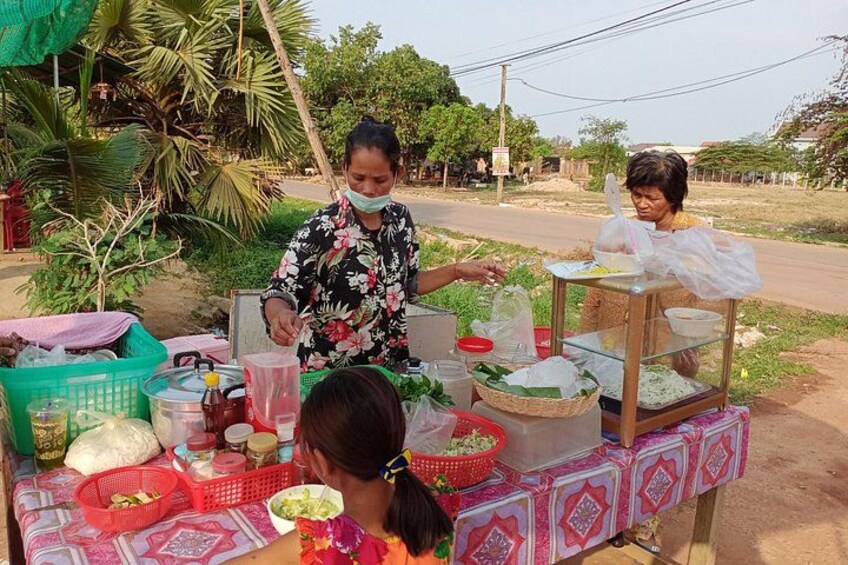 A street vendor stall with various food items and a customer. 4
