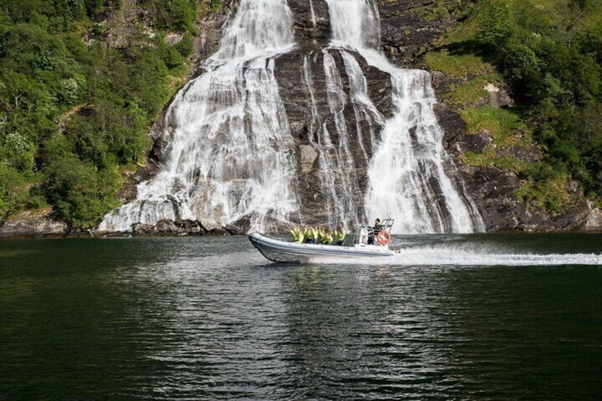 A boat with passengers near a waterfall. 1