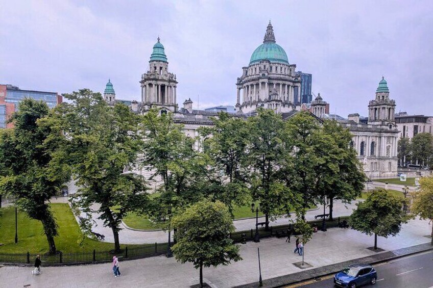 Un edificio histórico con torres en forma de cúpula, rodeado de árboles y un sendero pavimentado. 1