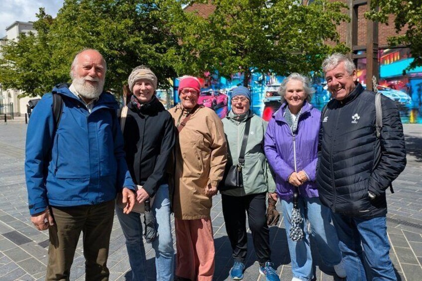 A group of people standing on a paved area with trees and buildings in the background. 4