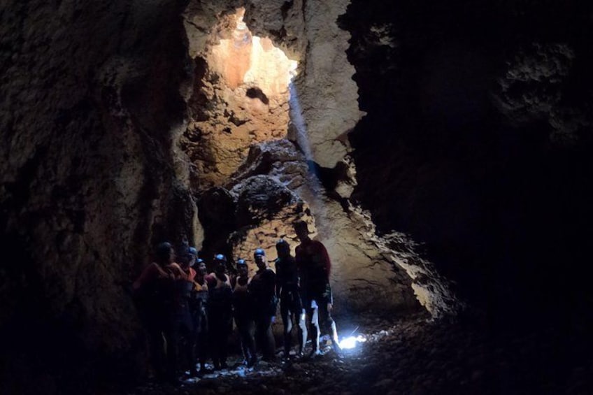 Un grupo de personas dentro de una cueva, con una fuente de luz al final de un pasaje. 3