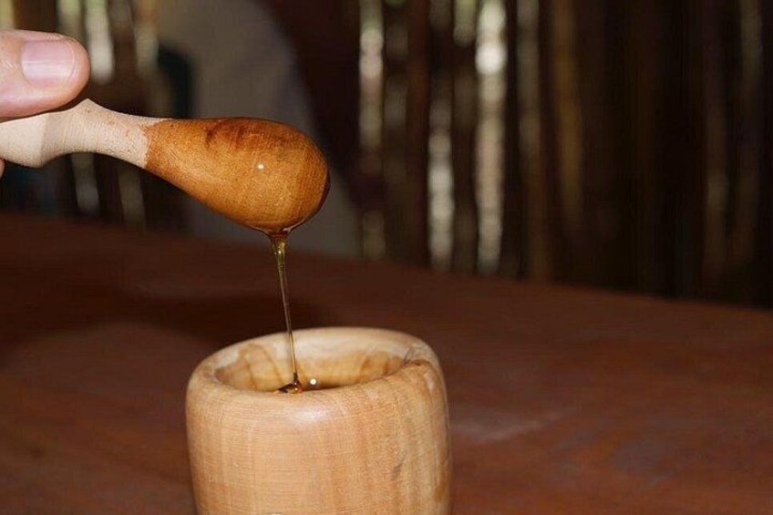 A wooden spoon pouring honey into a wooden cup. 5