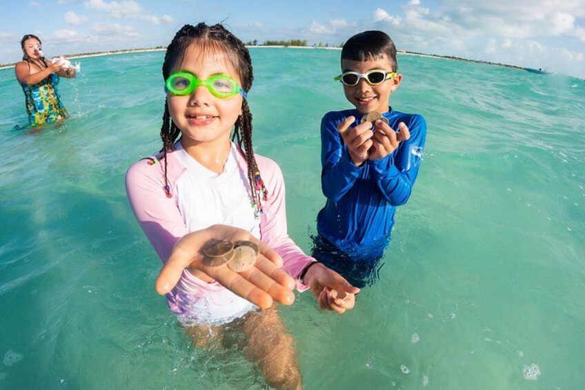Two people in shallow water holding seashells. 2