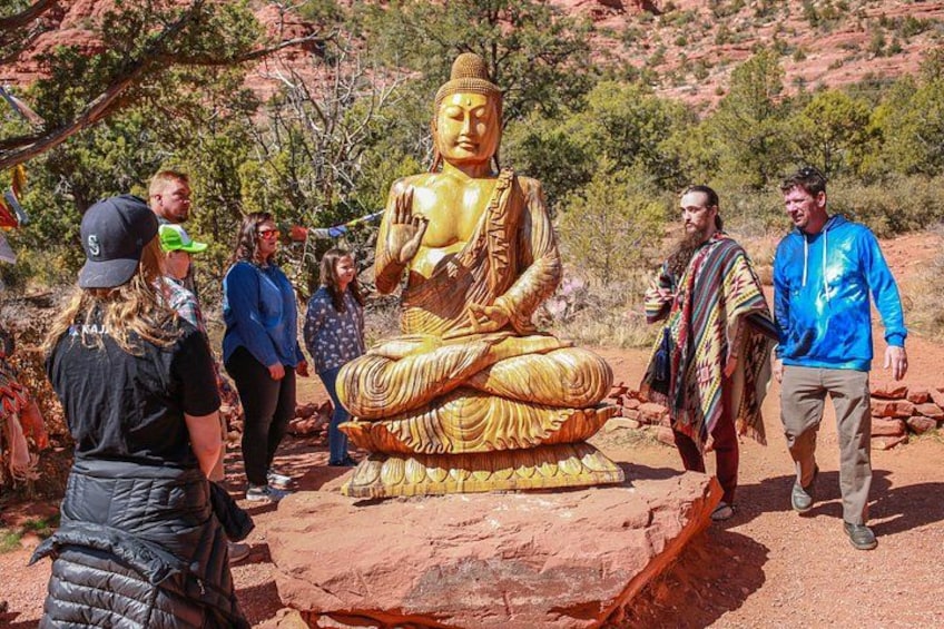 A large golden Buddha statue on a rock, surrounded by people. 2