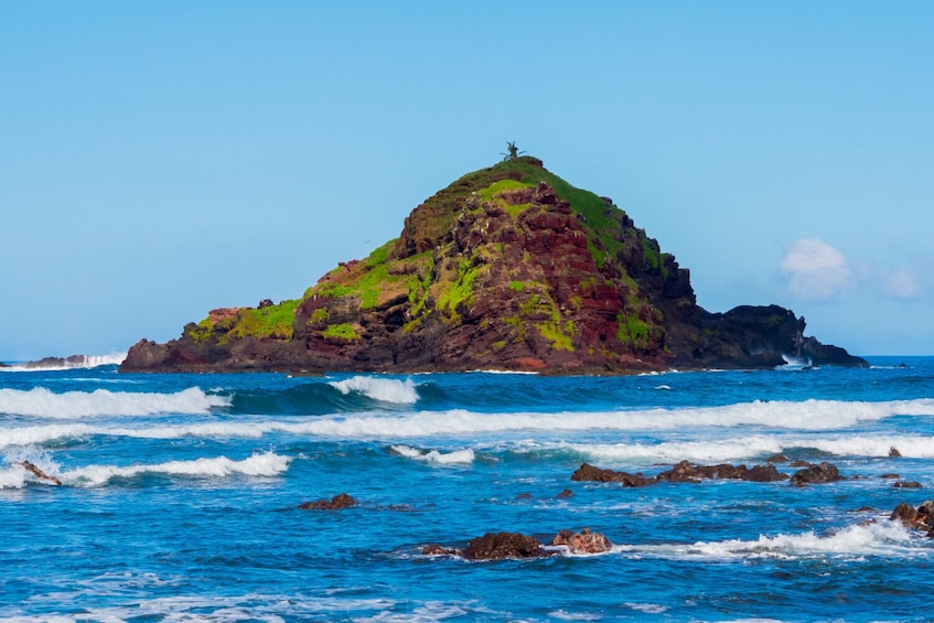A rocky island with waves crashing against it. 4