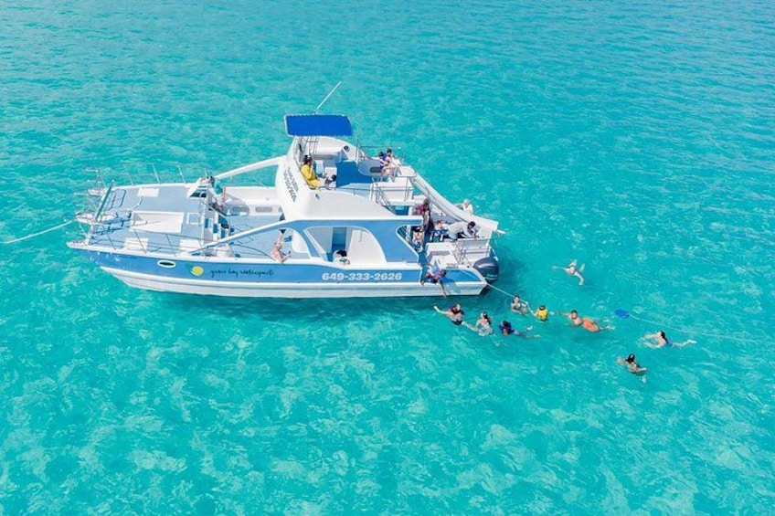 A boat with people swimming in the water nearby. 1