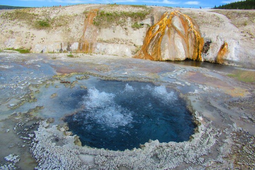 Un área geotérmica con un manantial termal, depósitos minerales y un paisaje rocoso. 2