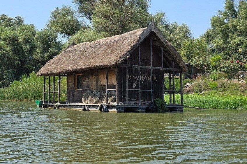 A wooden houseboat on a river surrounded by greenery. 2