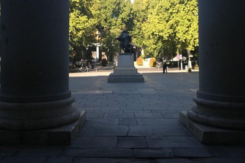 A paved pathway flanked by large stone columns leading to a statue. 3