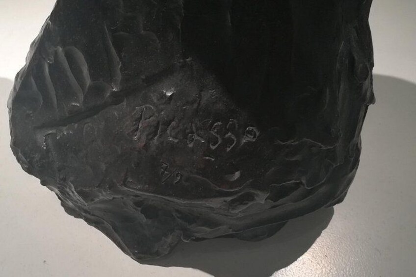 En mørk, struktureret overflade med præget tekst der viser 'Picasso 1930'. 2