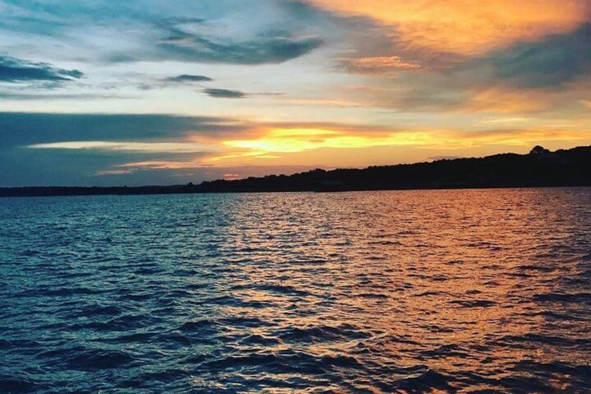 A sunset over a body of water with a silhouette of land in the distance. 1