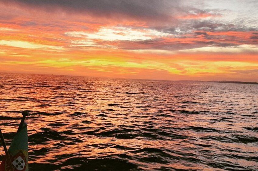 A sunset over a body of water with a boat in the foreground. 2