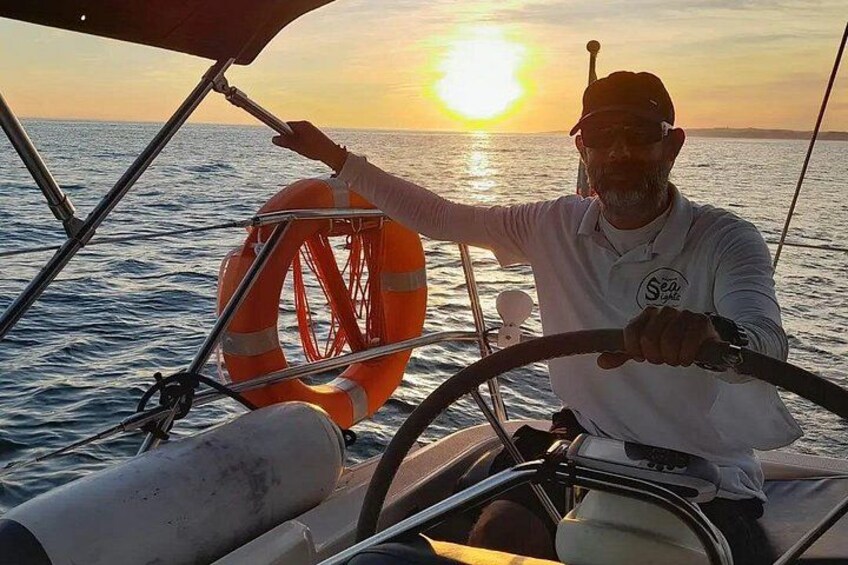 A person steering a boat with a life buoy and a sun in the background. 2