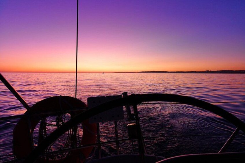 A boat's steering wheel and part of the deck at sunset. 3