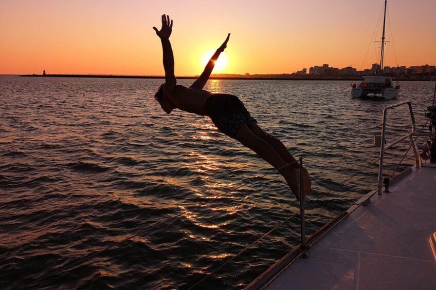 A person performing a handstand on a boat at sunset. 1