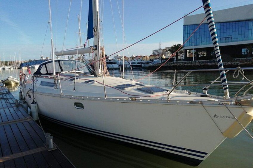 A sailboat docked at a marina with a building in the background. 5