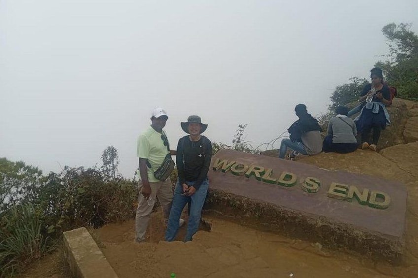 A group of people standing on a hill with a sign that reads 'WORLD'S END'. 1