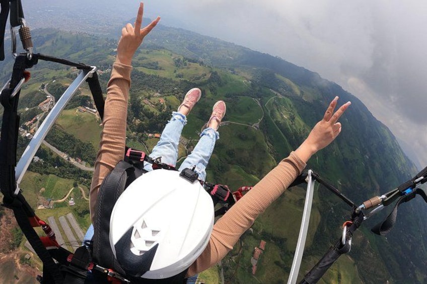 Eine Person mit ausgestreckten Armen, Helm und Fallschirmgurten beim Fallschirmspringen. 3