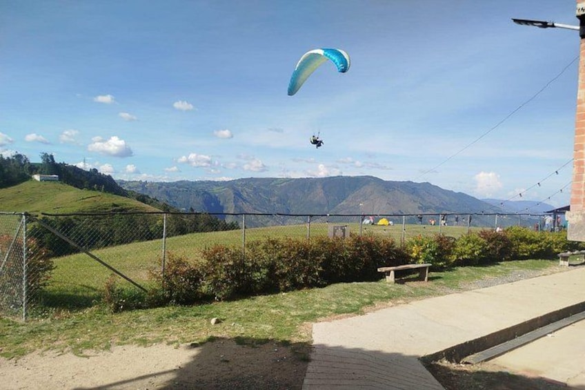 Eine Rasenfläche mit einem Zaun, einer Bank und einem Drachen am Himmel. 2