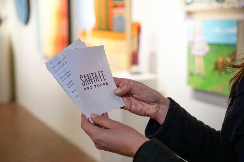 Eine Person hält eine Broschüre mit dem Titel 'SANTAAE ART TOURS'. 2