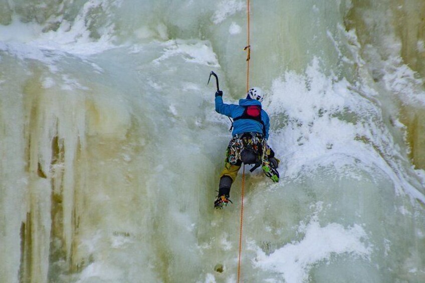 A person ice climbing on a frozen waterfall. 5