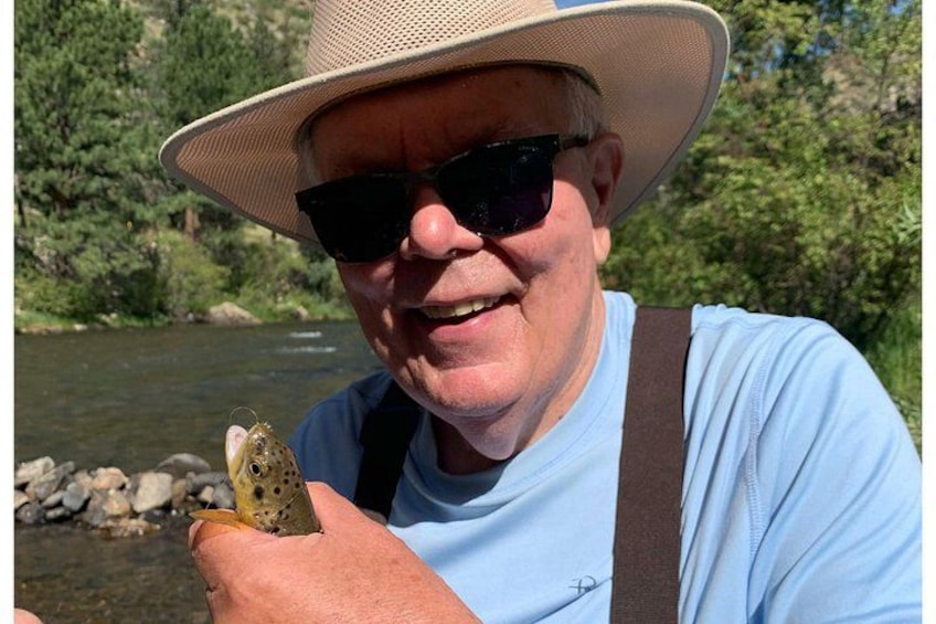 A person holding a frog near a river with trees in the background. 2