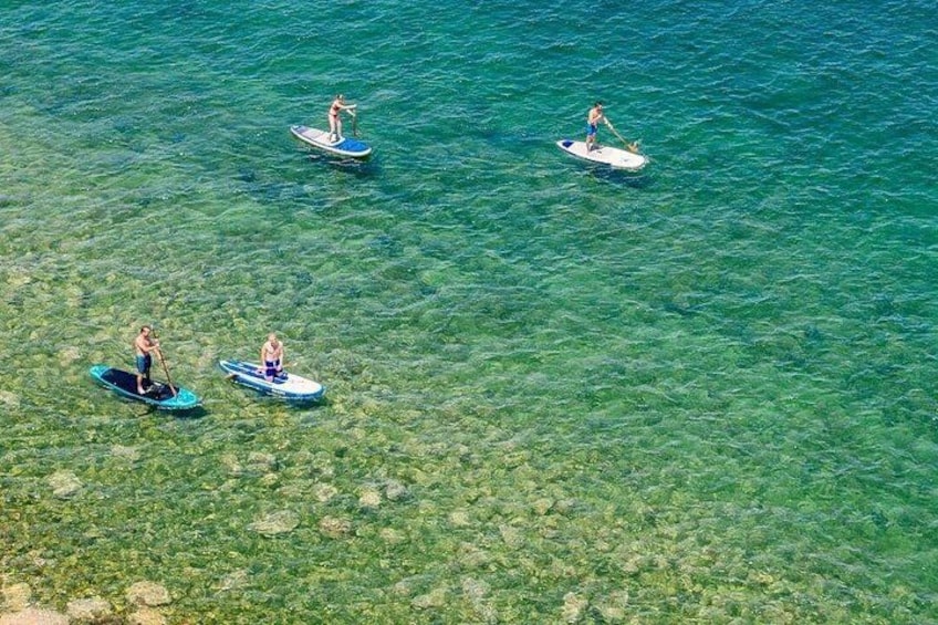 People paddleboarding on clear turquoise water. 5