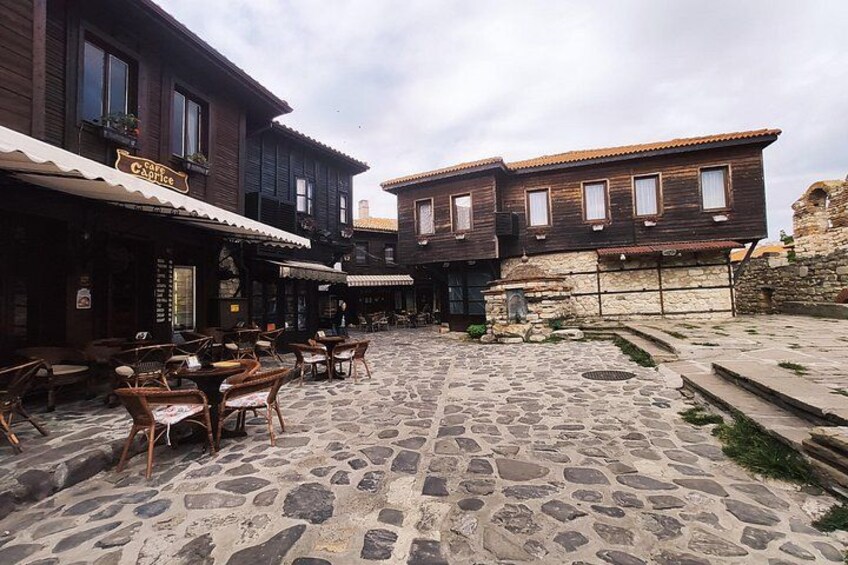 Un cortile in pietra con edifici in legno, posti a sedere all'aperto e un muro di pietra. 5