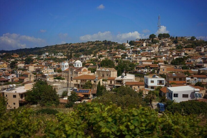 A densely populated hillside town with a prominent church, a transmission tower, and a mix of residential buildings. 2